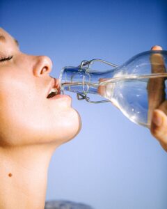 girl drinking water from glass bottle